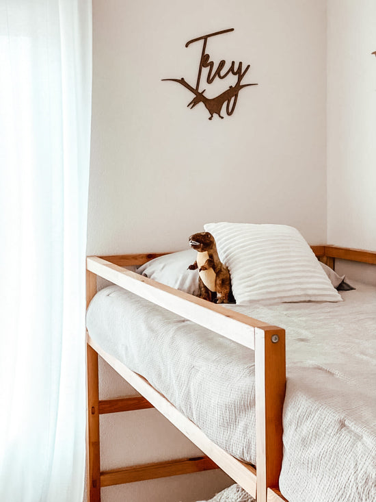 Dinosaur personalized wooden name sign next to wooden bunkbed.