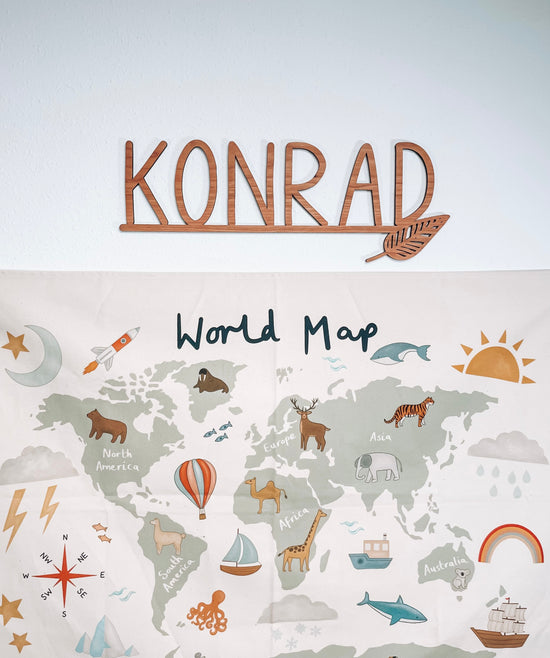 cut out name sign with leaf accent over an animal world map.