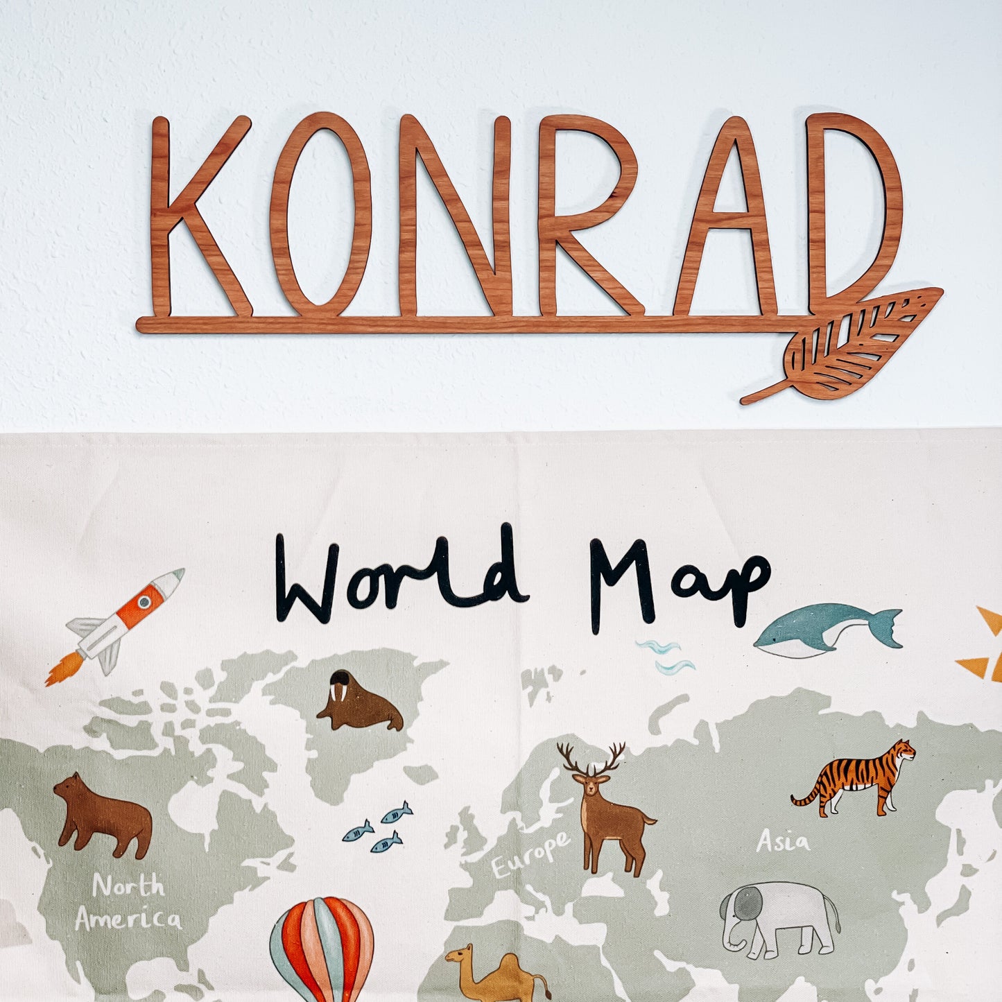 cut out name sign with leaf accent over an animal world map.