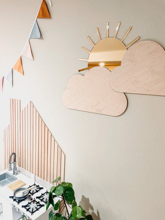 Boho sun & clouds, nursery wall decor, next to play pretend kitchen and colorful banner.