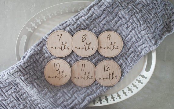 Baby milestone circles, milestone disks. Milestone circles displayed on a white platter with a gray cloth.