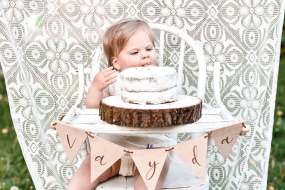Load image into Gallery viewer, Custom banner, pennant flags on a white wooden high chair with a baby sitting on it and a white cake on top.
