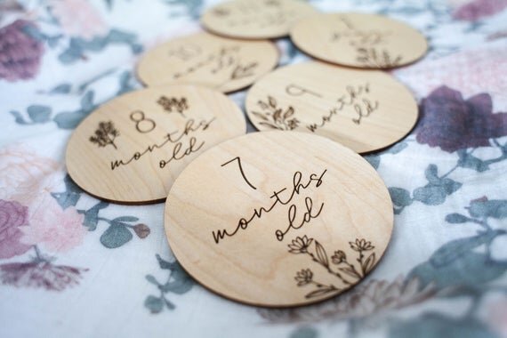 Botanical wooden baby milestone circles displayed on top of a floral sheet.