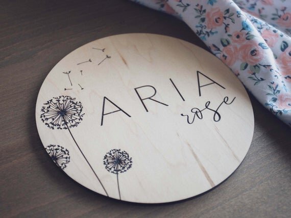 Dandelion engraved birth announcement plate next to floral sheet