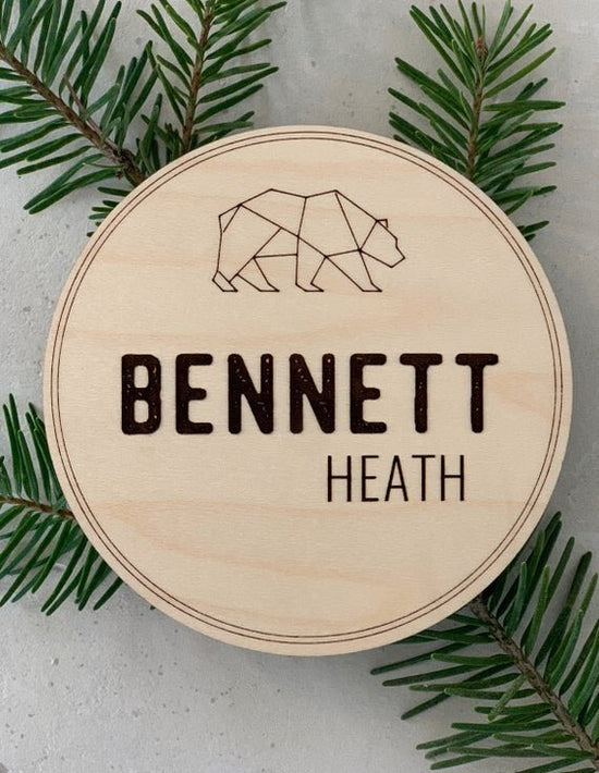 Bear Personalized Baby Name Announcement next to pine needle decor.