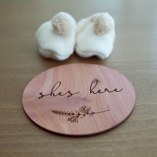 She's here red cedar wood birth announcement circle with white baby shoes