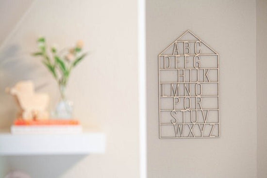 Load image into Gallery viewer, wooden alphabet house nursery decor on a white wall next to a shelf that has books and a plant in a vase

