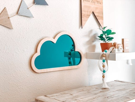 Blue cloud mirror, nursery wall decor next to shelf with boho decor.