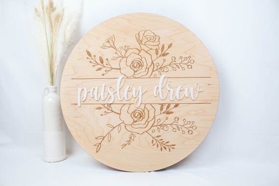 Baby Girl Nursery Sign with Floral Engraved Details next to botanical plant
