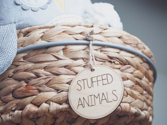 3" circular wooden toy storage tags on a wicker basket filled with stuffed animals