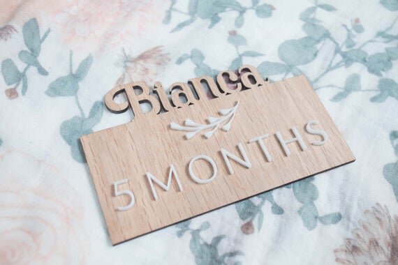 Custom wooden baby milestones, 3D milestone plaques with name on a floral sheet.