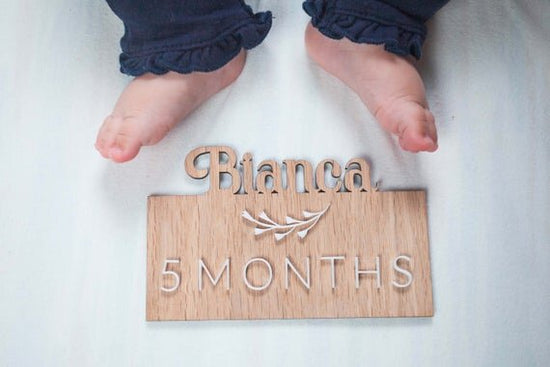 Custom wooden baby milestones, 3D milestone plaques with name next baby feet.