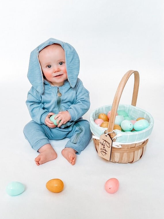 3.5" personalized wooden tags on Easter basket filled with colorful eggs with baby in a blue bunny onesie playing with Easter eggs