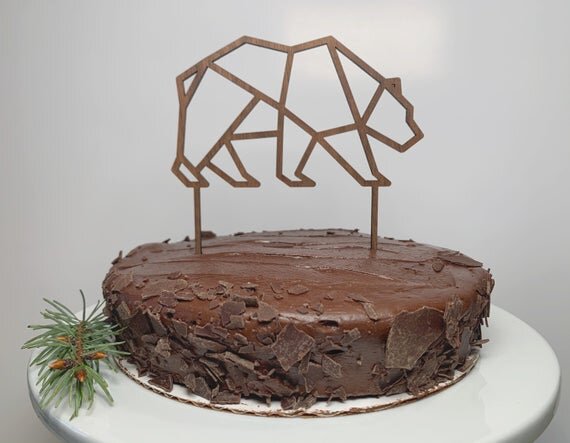 Bear cake topper, birthday cake topper, minimalistic cake topper, on a chocolate cake, next to pine needle decor.