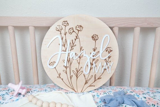 Load image into Gallery viewer, baby girl nursery name sign with botanical details inside wooden crib next to pink pacifier, white onesie, and blue bow
