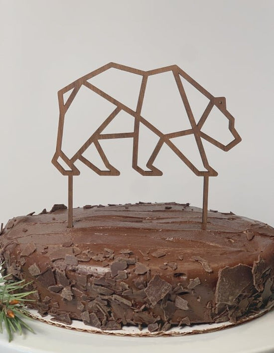 Bear cake topper, birthday cake topper, minimalistic cake topper, on a chocolate cake, next to pine needle decor.