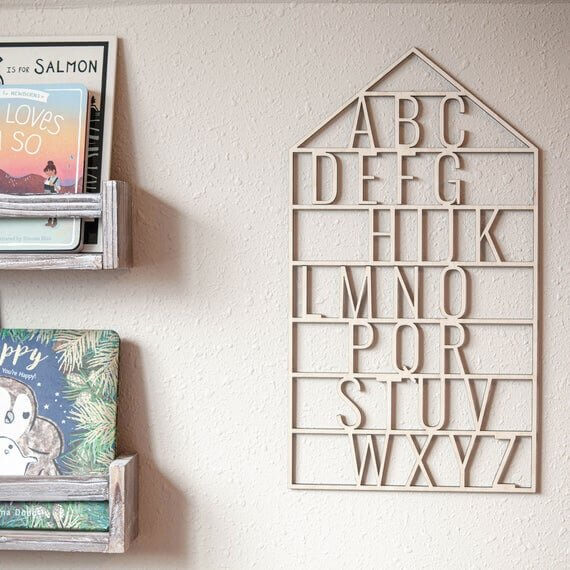 wooden alphabet house nursery decor next to wooden shelves filled with books