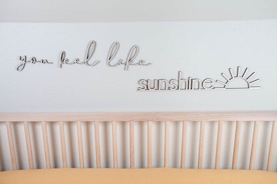 you feel like sunshine above the crib cut out sign on a white wall next to a wooden crib