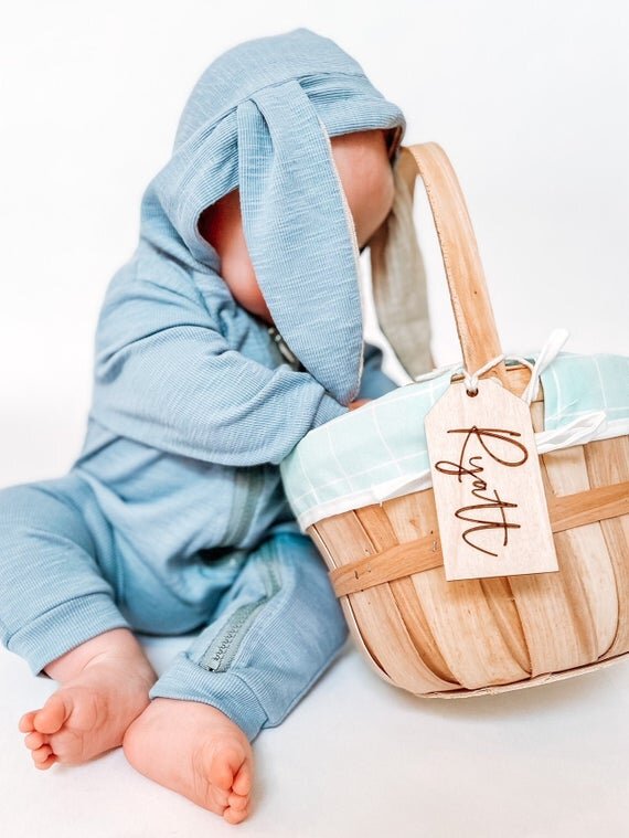 3.5" personalized wooden tags on Easter basket with baby in a blue bunny onesie reaching into the basket