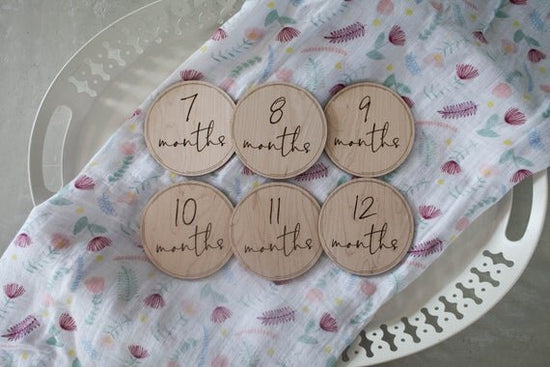 Baby milestone circles, milestone disks. Milestone circles displayed on a white platter with a colorful cloth.