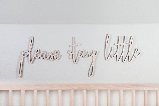 please stay little above the crib cut out sign on a white wall next to a wooden crib