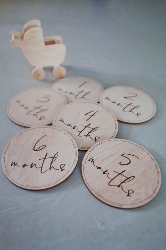 Baby milestone circles, milestone disks. Milestone circles displayed next to a small wooden stroller.