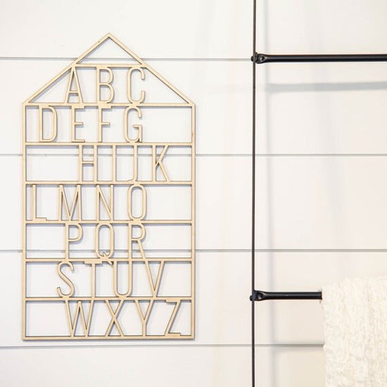 Load image into Gallery viewer, wooden alphabet house nursery decor next to black rack with hanging white throw
