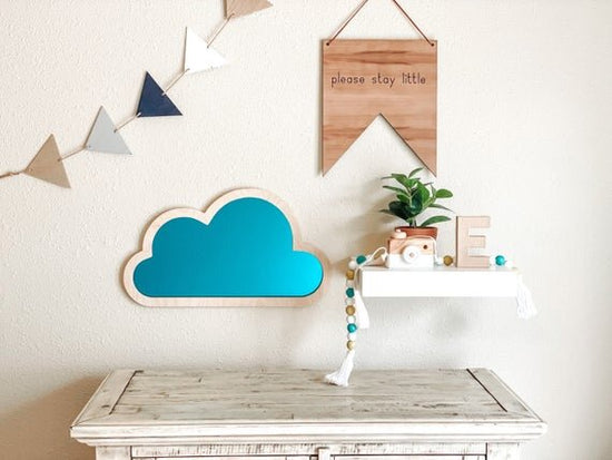 blue cloud nursery decor next to pennant flag and please stay little quote nursery sign